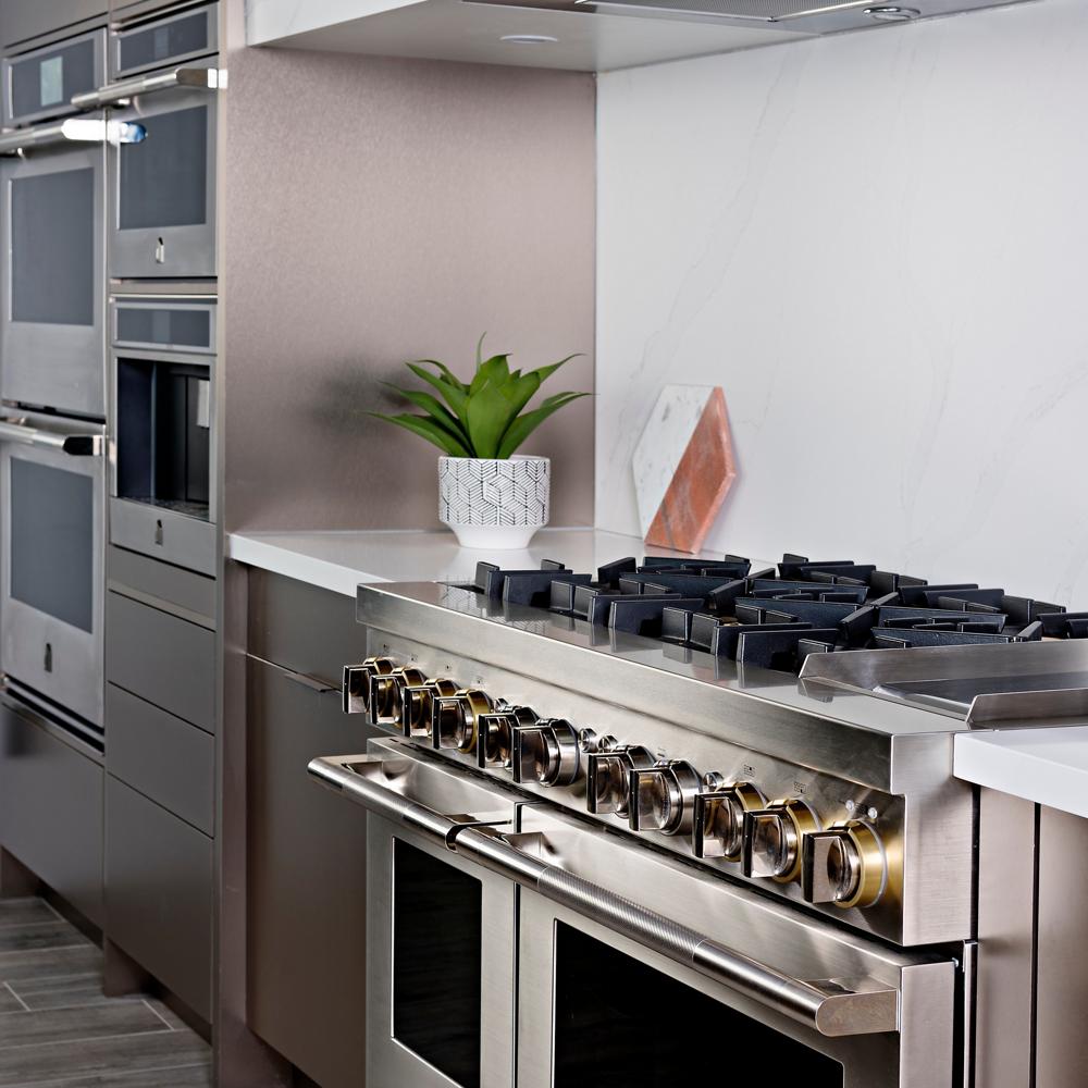 Four mural JennAir en acier inoxydable dans une cuisine aux côtés d'une planche à découper, une plante et d'autres électroménagers JennAir.