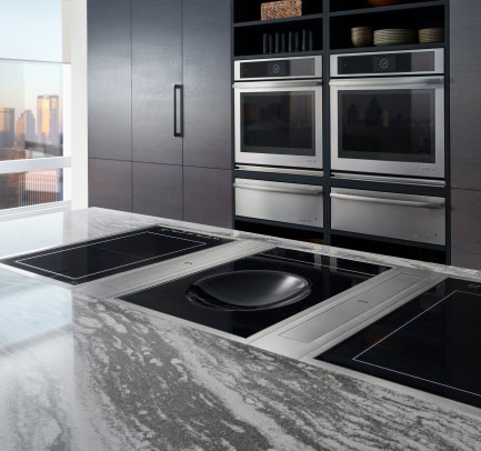 A kitchen with a JennAir Double Wall Oven surrounded by black cabinets. Built into the island is a JennAir Induction Cooktop.  A kitchen with a JennAir Double Wall Oven surrounded by black cabinets. Built into the island is a JennAir Induction Cooktop.