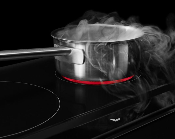 On a JennAir Ceramic Cooktop is a boiling pot on an activated burner with steam coming out of it