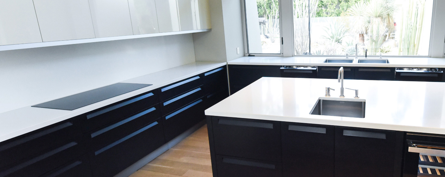 A kitchen with an island with a sink. On the counters is a JennAir Ceramic Cooktop and another sink