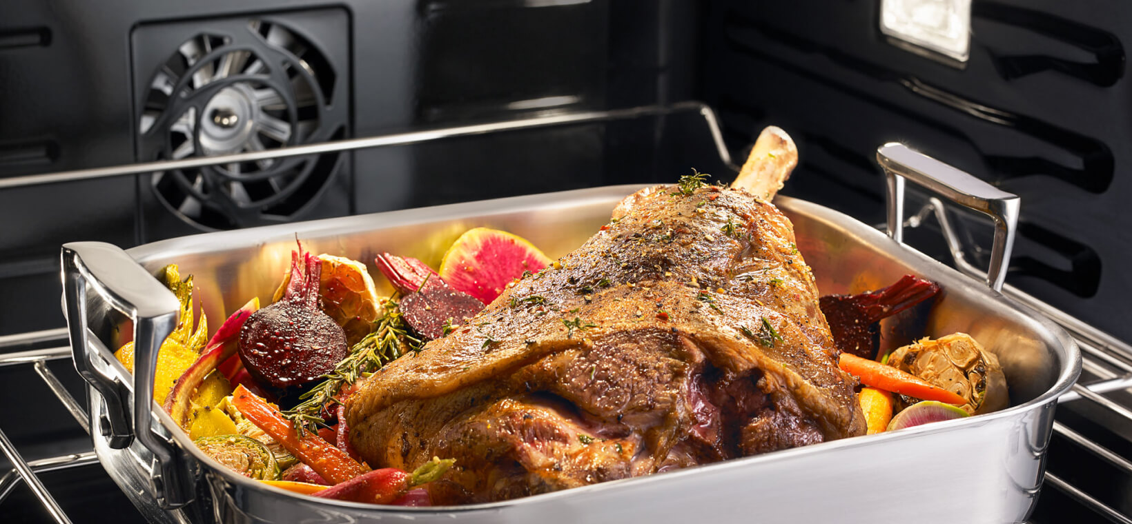 A lamb shank bakes in an oven dish inside a JennAir oven.
