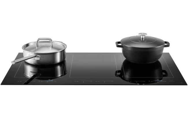 An induction cooktop. On one burner is a large pan. On the other other is a Dutch oven