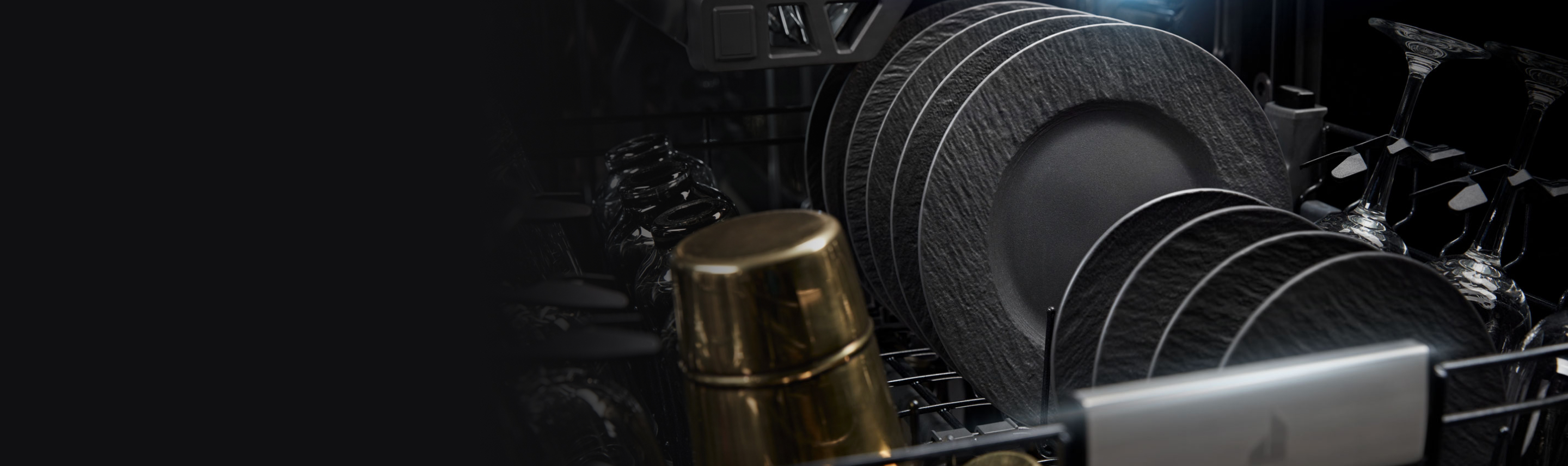 L'intérieur d’un lave-vaisselle JennAir. Un panier est rempli de tasses, verres à vin et assiettes.