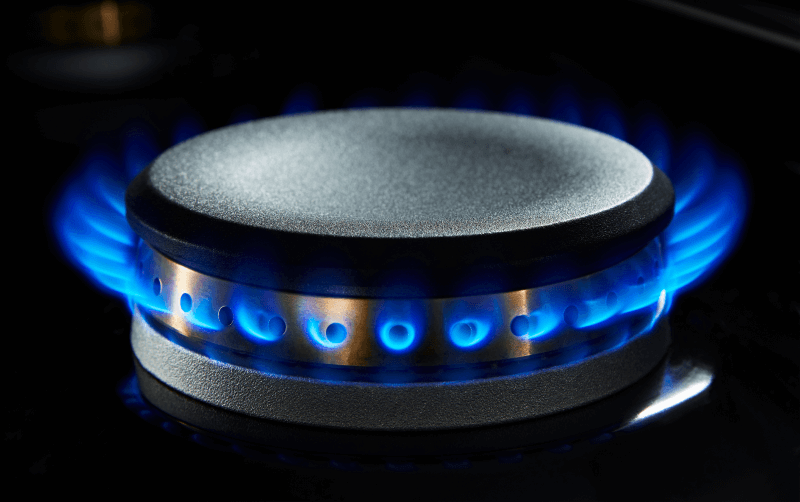 An activated burner on a JennAir dual-fuel range with a blue flame