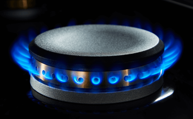 An activated burner on a JennAir dual-fuel range with a blue flame