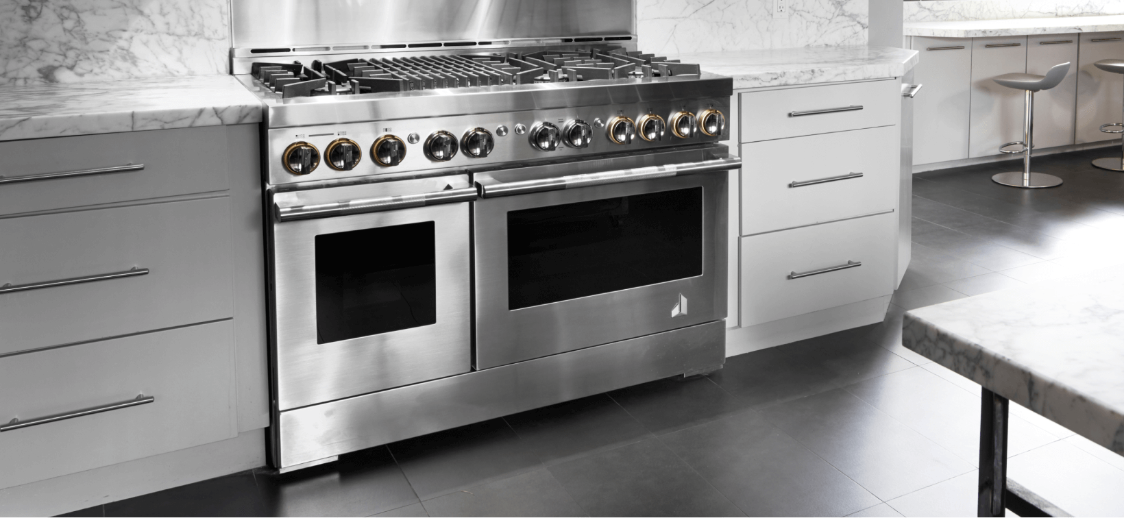 A high-end kitchen with JennAir double oven. Nearby are stools. 