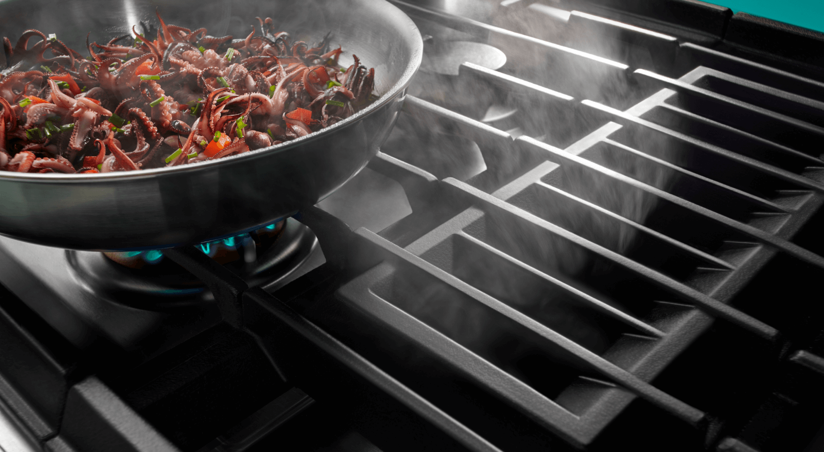Image of food items cooking on a grill section of a downdraft range, emphasizing the direct heat. Image of food items cooking on a grill section of a downdraft range, emphasizing the direct heat.
