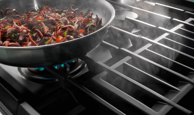 Image of food items cooking on a grill section of a downdraft range, emphasizing the direct heat. Image of food items cooking on a grill section of a downdraft range, emphasizing the direct heat.
