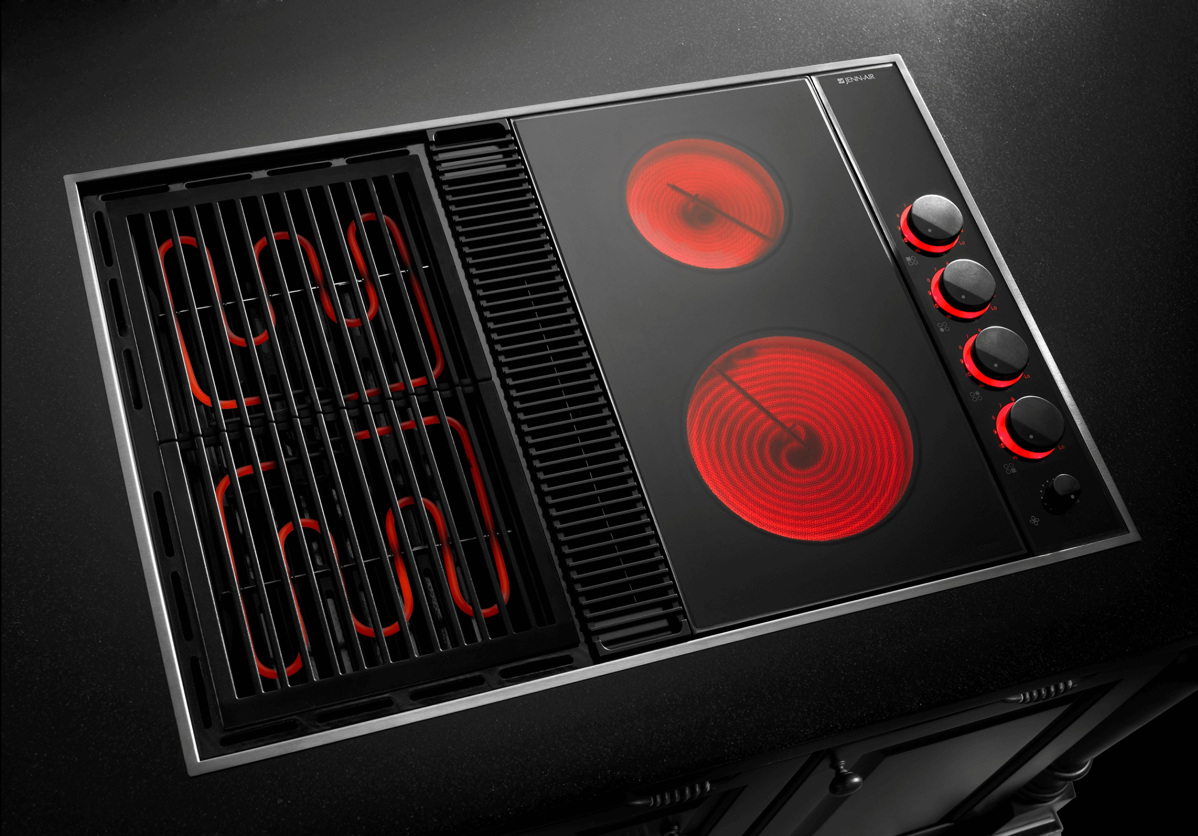 A downdraft cooktop with red heating elements, highlighting the combination of electric cooking and integrated ventilation. A downdraft cooktop with red heating elements, highlighting the combination of electric cooking and integrated ventilation.
