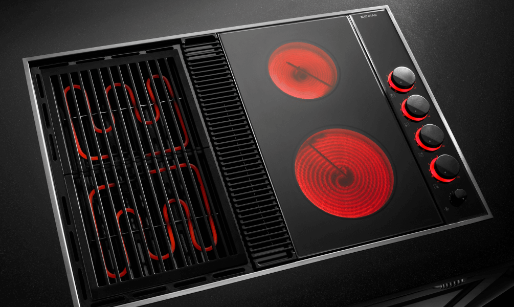 A downdraft cooktop with red heating elements, highlighting the combination of electric cooking and integrated ventilation. A downdraft cooktop with red heating elements, highlighting the combination of electric cooking and integrated ventilation.