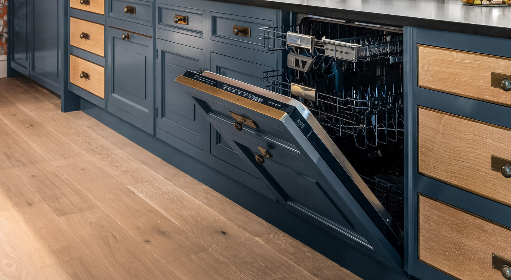  A kitchen with an opened JennAir panel-ready dishwasher that matches the blue and wood patterned cabinetry.