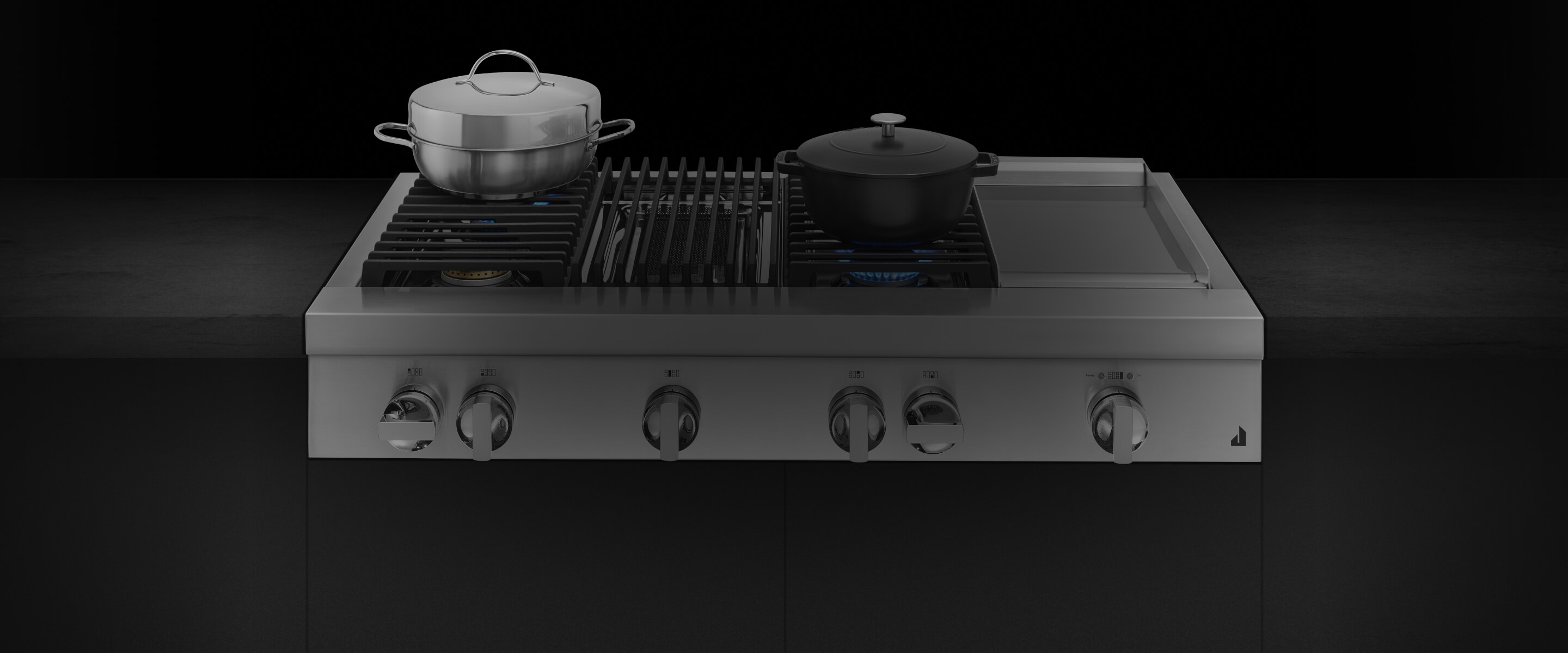 A JennAir® NOIR™ Design rangetop with pans and cookware on top.