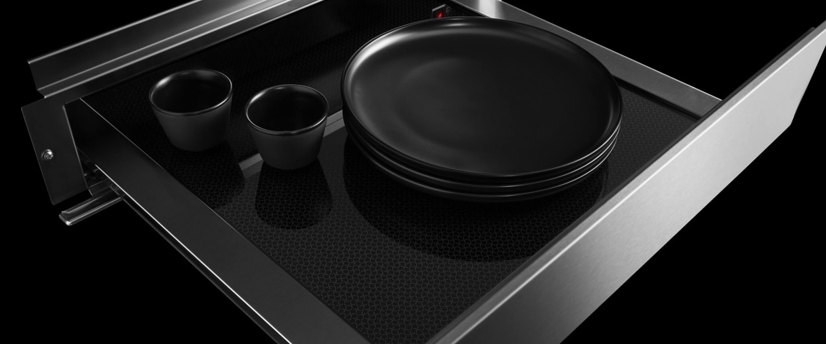 An open JennAir® warming drawer filled with plates and mugs.