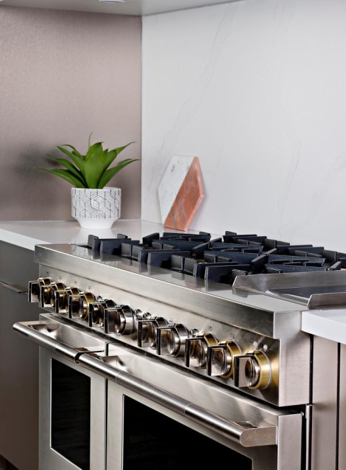 JennAir stainless steel wall oven in a kitchen alongside a cutting board, plant and other JennAir appliances.