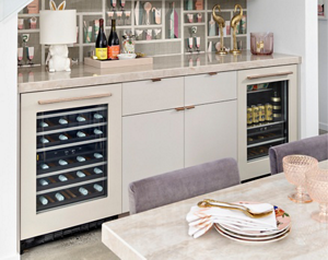 A kitchen with two JennAir Beverage Centres. On the counter is a tray with two wine bottles and shelves of wine glasses.