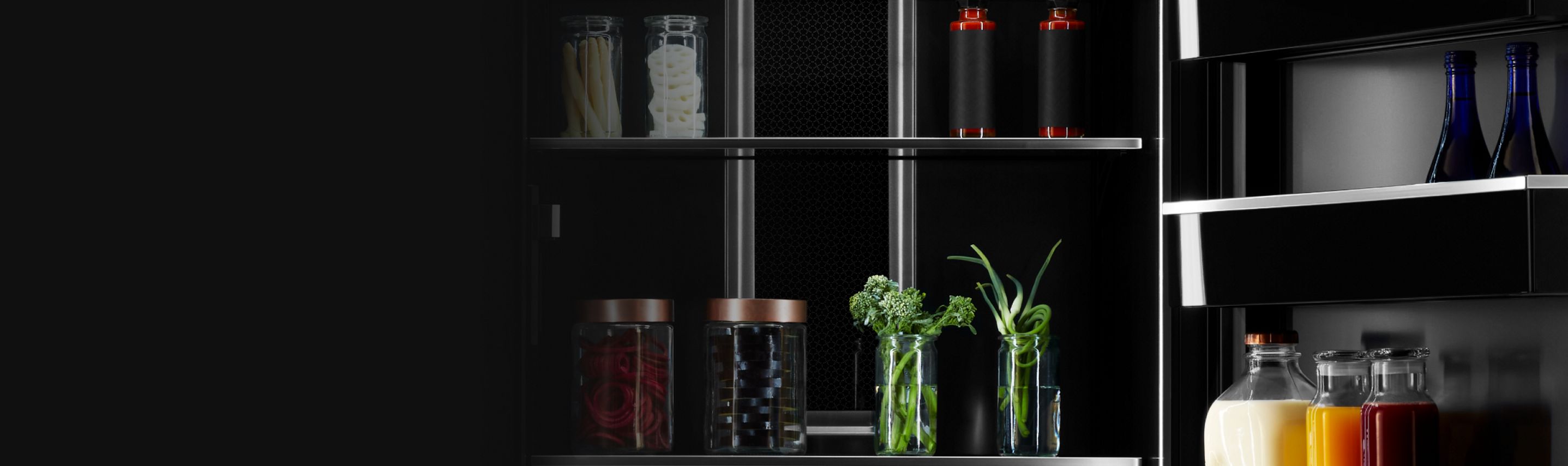 Intérieur d’un réfrigérateur JennAir rempli d’articles comme des fines herbes dans des verres, des boissons et des condiments.
