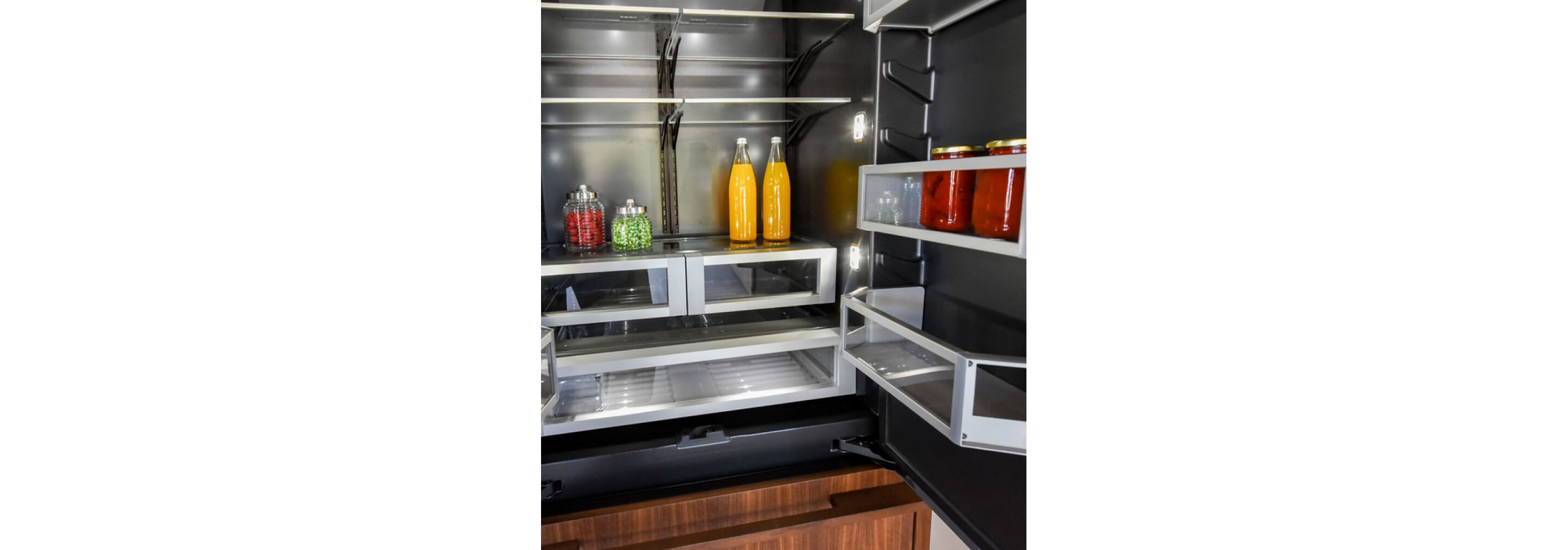 The interior of a JennAir® Built-In Refrigerator with LED theater lighting illuminating each corner of the shelving.