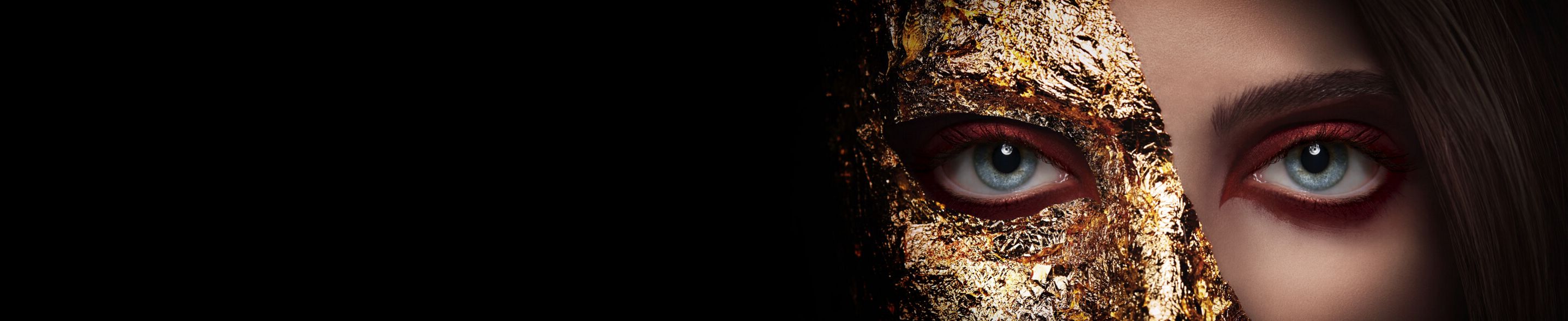 A woman's face half obscured by golden foil.