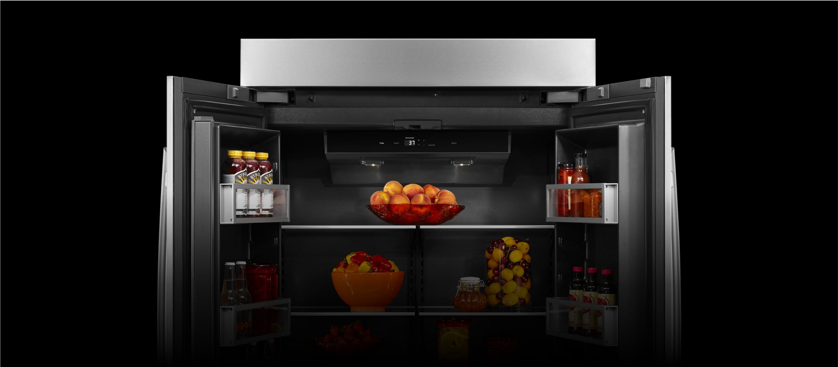 An open JennAir[®] high-end built-in refrigerator filled with vibrant orange fruit.