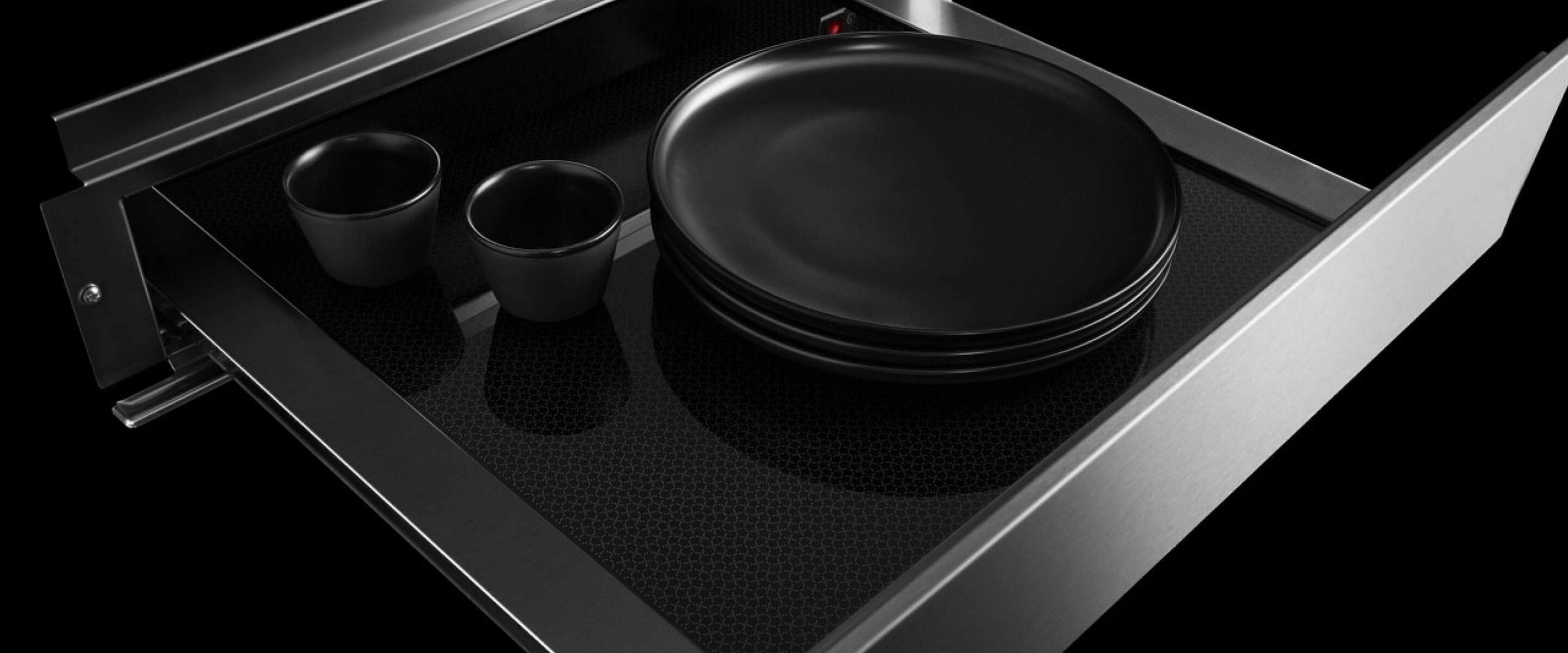 An open JennAir® warming drawer filled with plates and mugs.